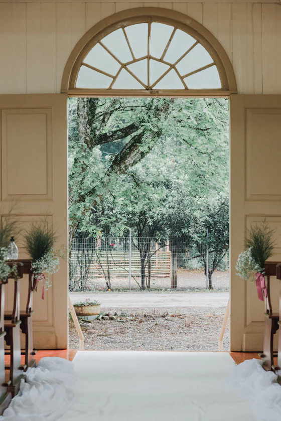 An open arched doorway framing green trees beyond a pale interior.
