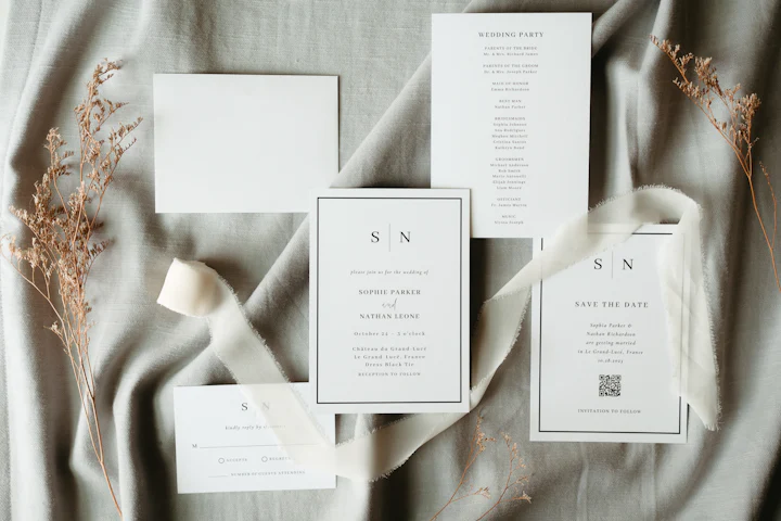 A monogrammed invitation suite laid across soft grey linen.