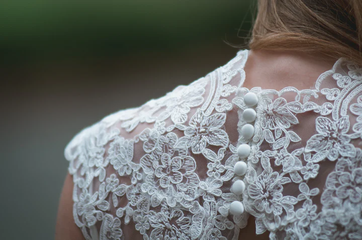 Close view of a lace bodice with a line of small covered buttons.