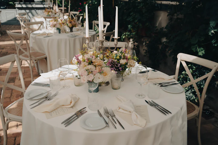 A round table with soft garden flowers in small vases and tall white candles.