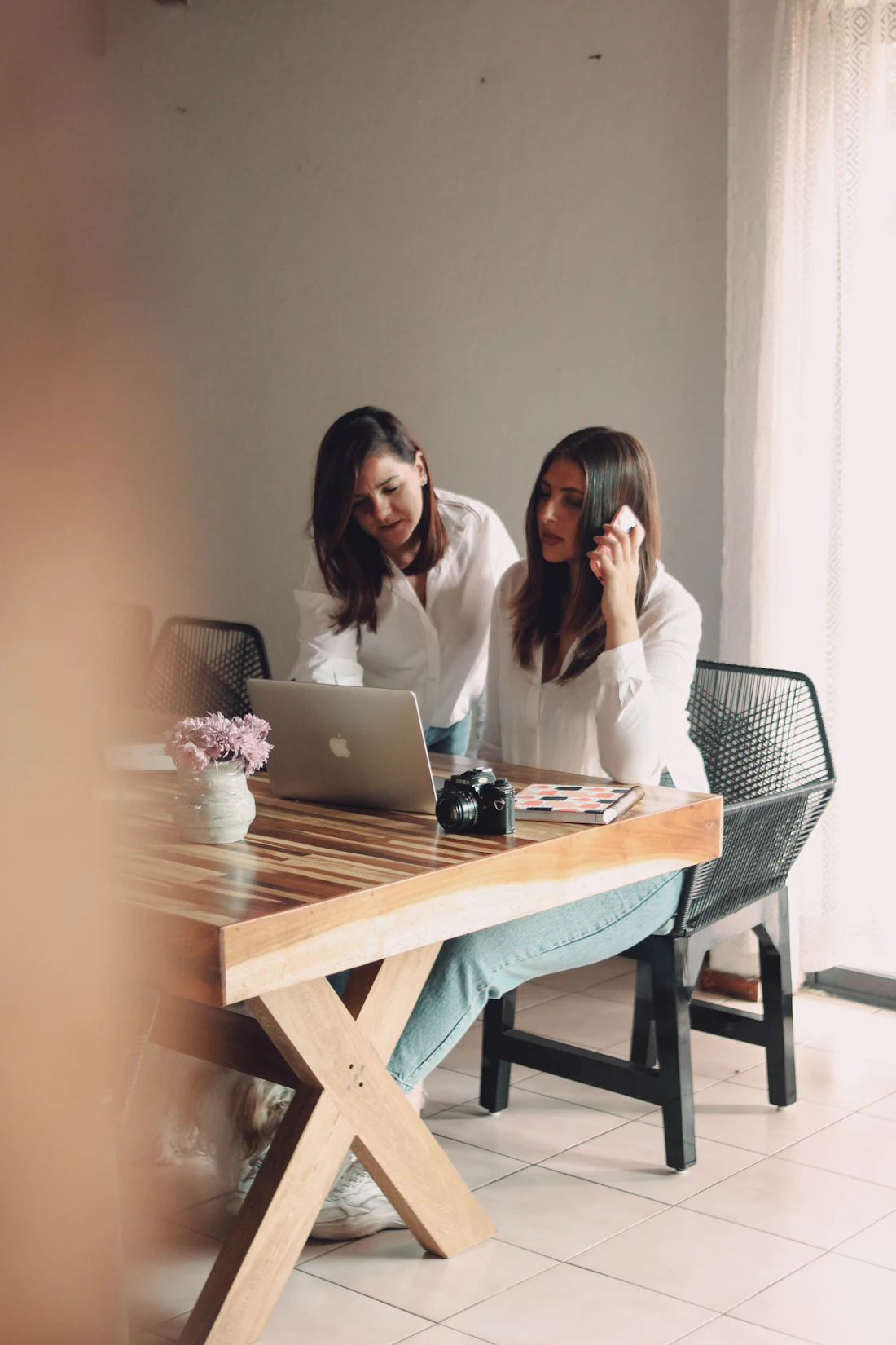 Two planners reviewing a wedding design on a laptop at a wooden worktable.