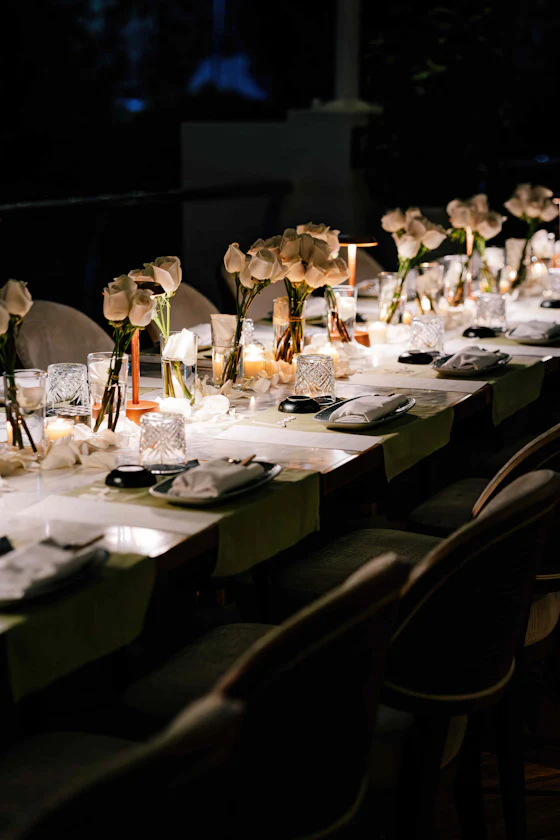 A long table set at night with flowers and small candles.
