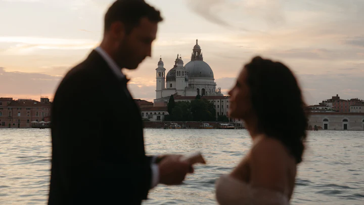 A couple silhouetted against the Venice skyline at sunset.